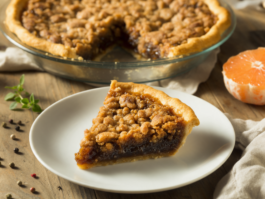 Slice of wet-bottom shoofly pie on a white plate showing crumb top over a dark molasses layer
